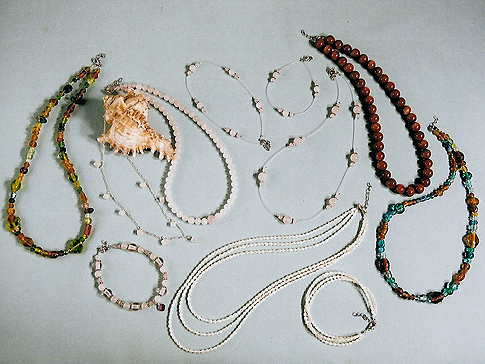 On left & far right: Antique beads in earth tones both $28.00 Sterling Necklace with Rose Quartz squares $30.00 Bracelet $25.00 Illusion Necklace $18.00 Bracelet $7.95 Anklet $12.95 Fresh Water Pearls 3-string Necklace $58.00 Bracelet $34.00 On top right: Sunstone/Goldstone beads $32.00